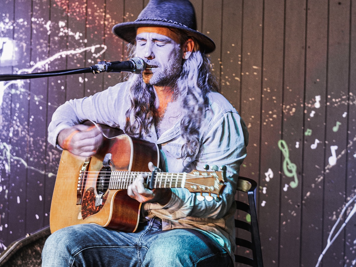 Guy wearing cowboy hat and singing with guitar