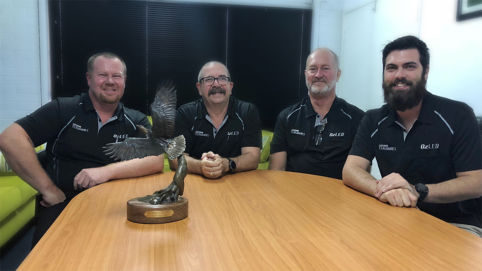 Guys around table with award on it